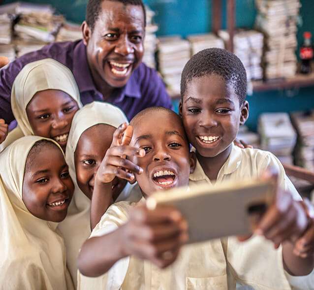 children and teacher looking at phone taking a selfie